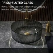 Prism-fluted glass sink on a dark marble countertop with gold fixtures.