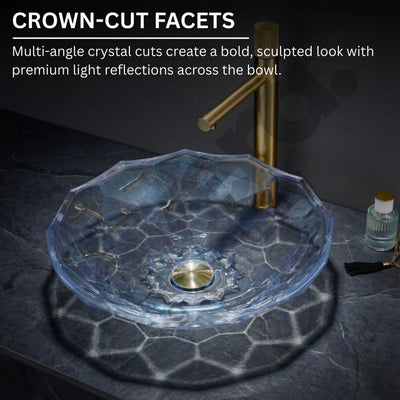 Glass sink with gold faucet on a dark surface, featuring crown-cut facets.