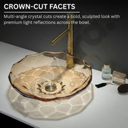 Glass sink with gold faucet on a white surface, featuring crown-cut facets.