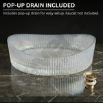 Clear glass sink basin with pop-up drain on a dark marble surface