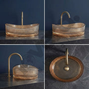Bathroom sink with gold faucet on a dark surface against a blue wall