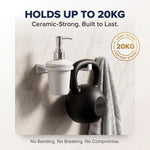 White ceramic soap dispenser with a black kettlebell on a marble surface, emphasizing durability.