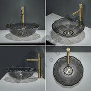 Gray glass sink with gold faucet on a white surface against a dark background